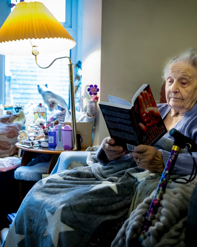 An older woman reading a book in an armchair